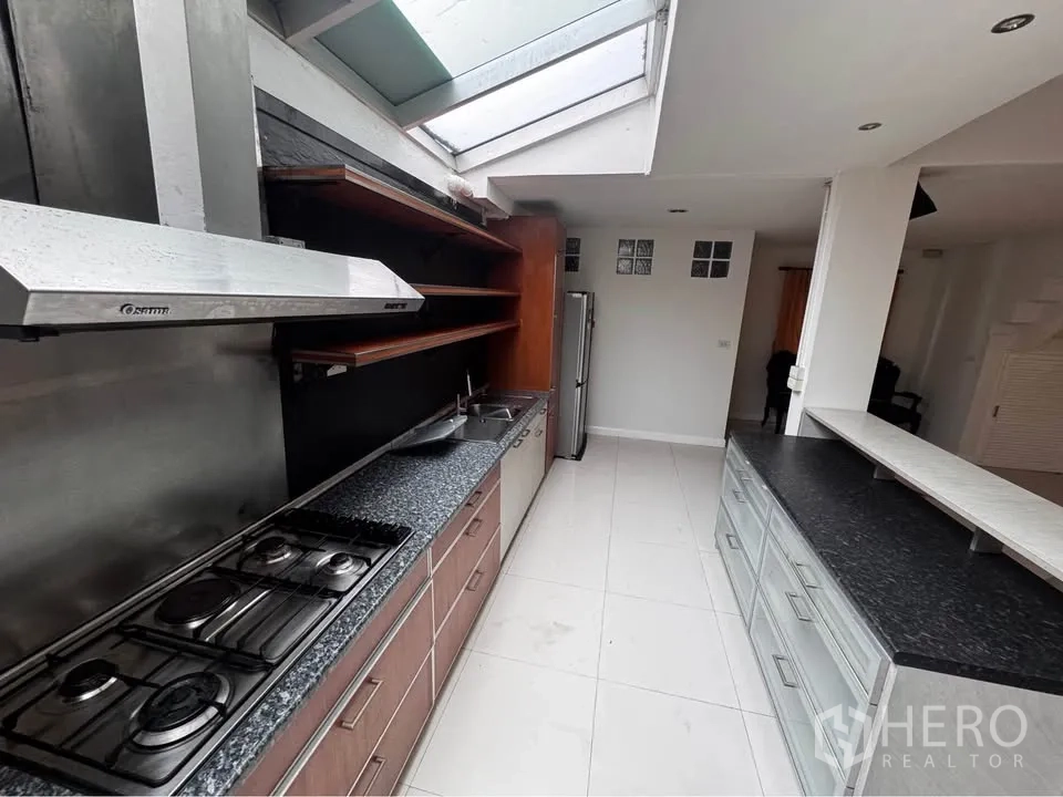Townhouse for rent in Huai Khwang, Bangkok - Kitchen with long countertops, gas hob, extractor hood and skylight.