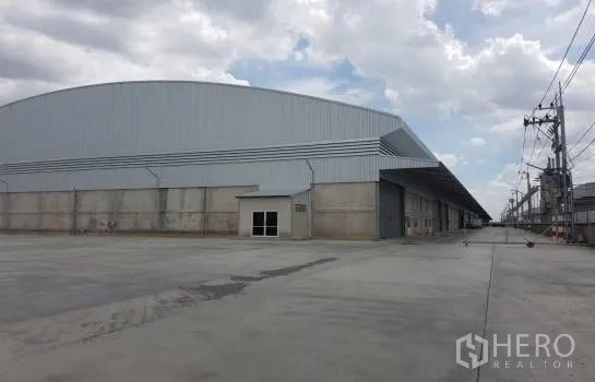 货栈 出租在Lam Luk Ka, Pathum Thani - 大型工业仓库转角视图，宽阔的混凝土场地。