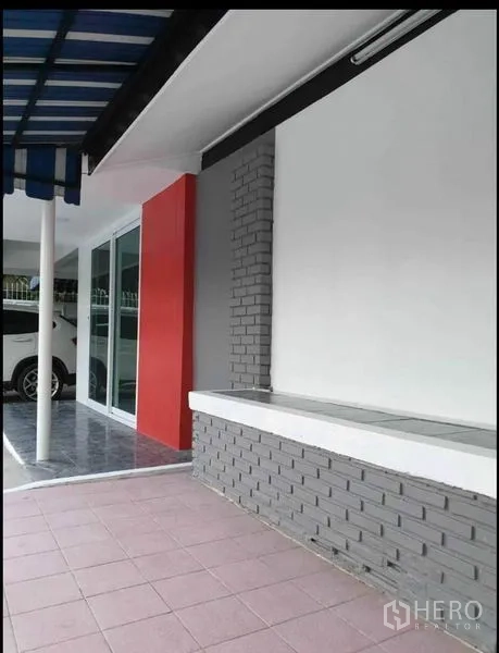 Detached House for rent in Lat Phrao, Bangkok - Covered entrance terrace with striped awning, red accent wall, sliding glass door and tiled patio.