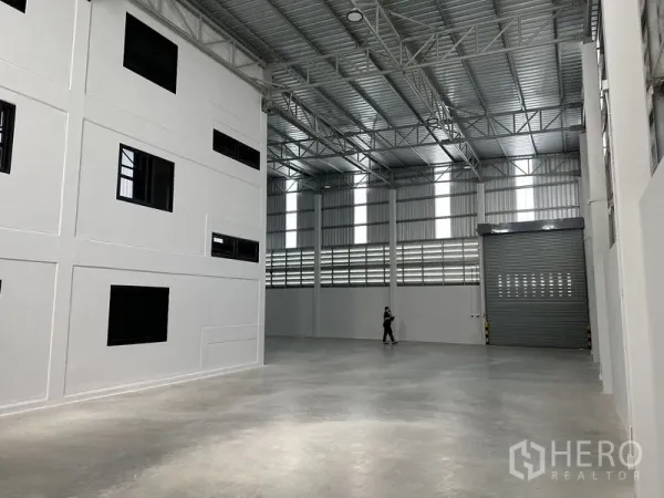 Warehouse for rent in Bang Phli, Samut Prakan - Bright warehouse hall with vertical skylight panels and a full-height roller door for truck access.