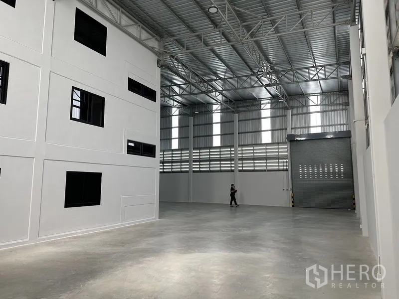 Warehouse for rent in Bang Phli, Samut Prakan - Bright warehouse hall with vertical skylight panels and a full-height roller door for truck access.