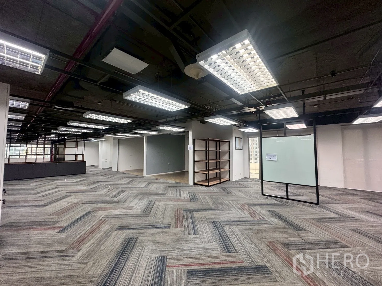 Office Space for rent in Watthana, Bangkok - Spacious zone with a movable glass whiteboard, shelving units, and carpet tile flooring.