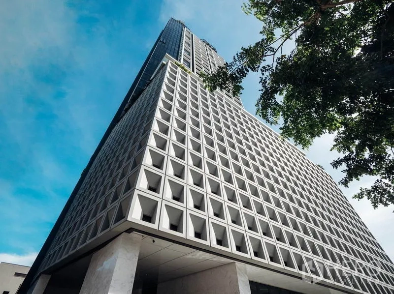Condominium for rent in Khlong Toei, Bangkok - High-rise condominium exterior with a geometric facade against a blue sky.