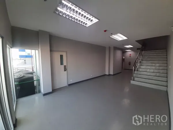 工厂 出租在Bang Lamung, Chon Buri - 一层办公大堂，楼梯、通往阳台的玻璃门与灰色地面