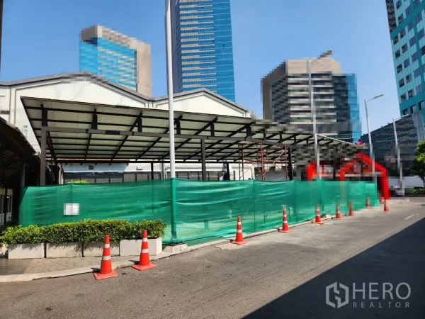 Retail Space for rent in Khlong Toei, Bangkok - Street-facing retail canopy with green hoarding and traffic cones, high-rise skyline in Khlong Toei near BTS Thonglor.