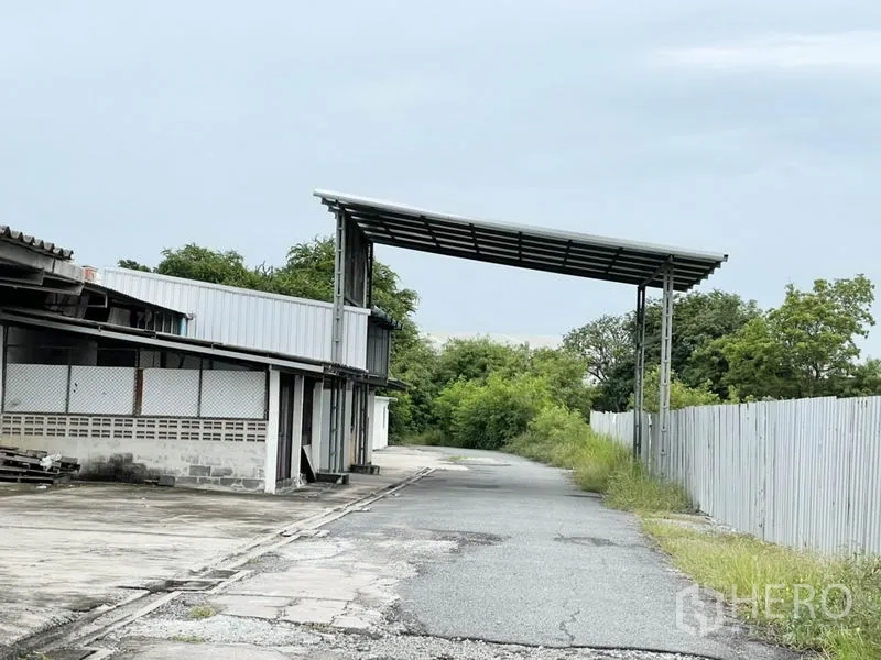 工厂 出租在Bang Pakong, Chachoengsao - 园区车道配有覆盖装卸雨棚及周界围栏，临近树木。