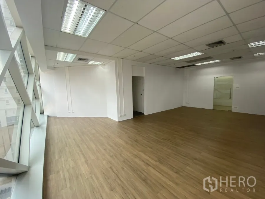 Office Space for rent in Watthana, Bangkok - Open office interior with glass entry, white walls, timber flooring and floor-to-ceiling windows.