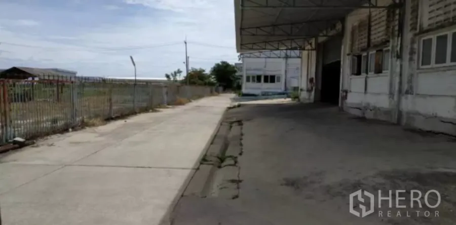 Factory for rent in Bang Pakong, Chachoengsao - Covered loading bay and concrete driveway beside a factory building with perimeter fencing.