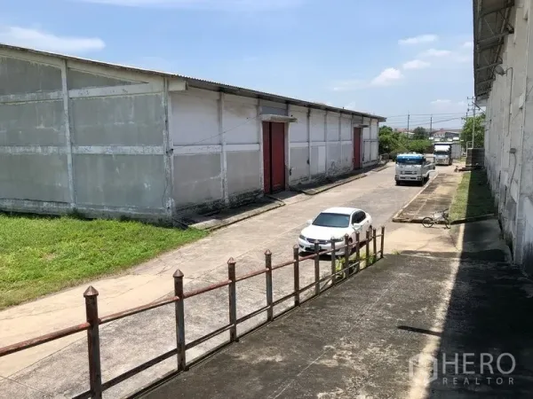 Factory for rent in Lat Krabang, Bangkok - Internal service road between warehouse blocks with trucks and a car.