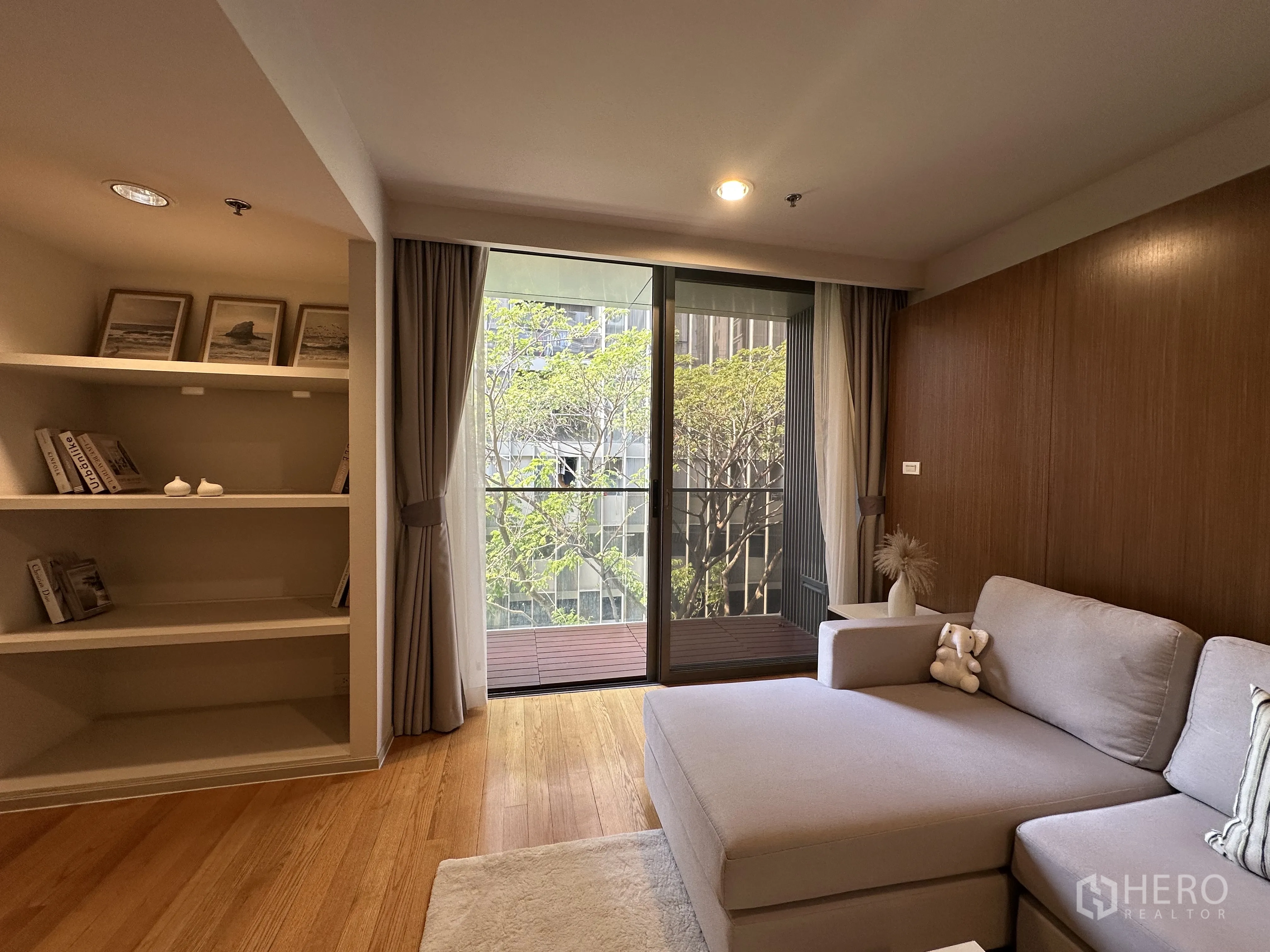 Condominium for rent in Khlong Toei, Bangkok - Reading nook with open shelves beside sliding glass doors to the balcony.