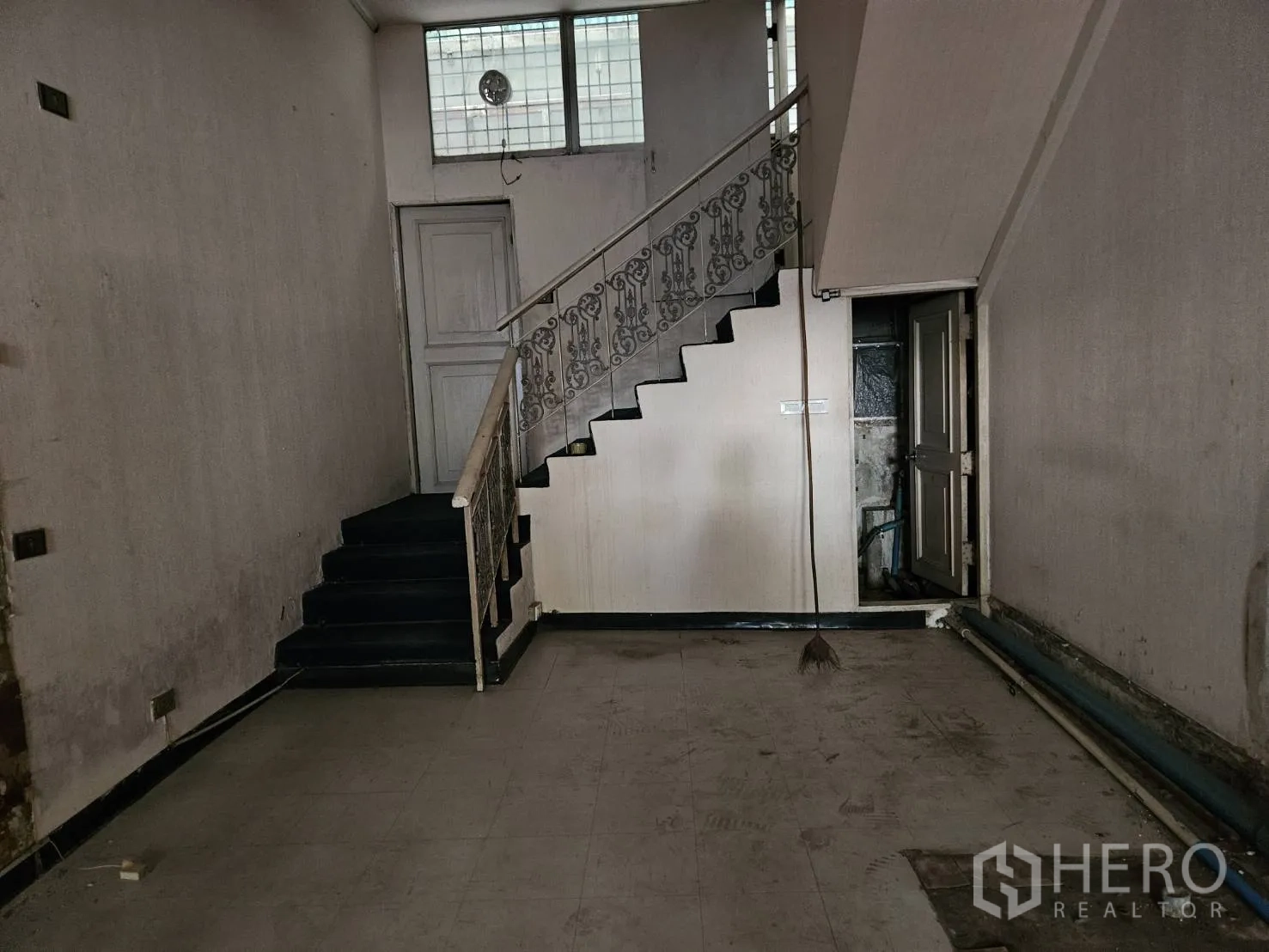 Shophouse for rent in Watthana, Bangkok - Ground-floor retail space with staircase, bare walls and tiled floor, ready for renovation.