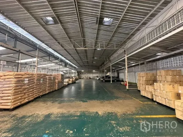 Warehouse for rent in Yan Nawa, Bangkok - Large Bangkok warehouse with metal truss ceiling, marked lanes and boxes stacked on pallets across an open floor.