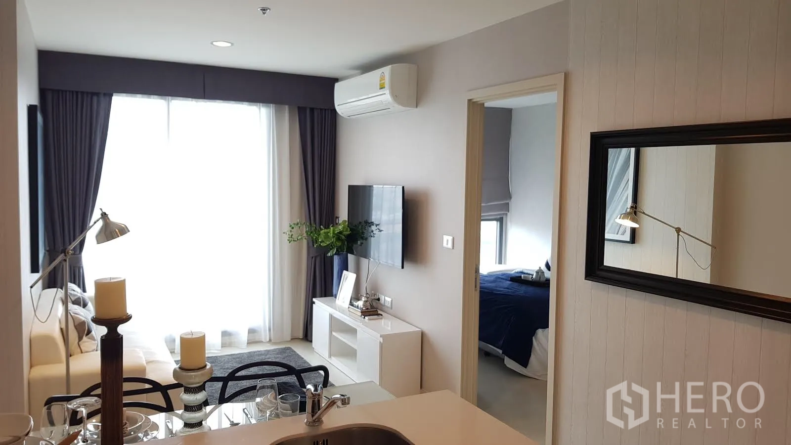 Condominium for rent in Khlong Toei, Bangkok - Open-plan living and dining area with sofa, TV wall and bright window glazing.