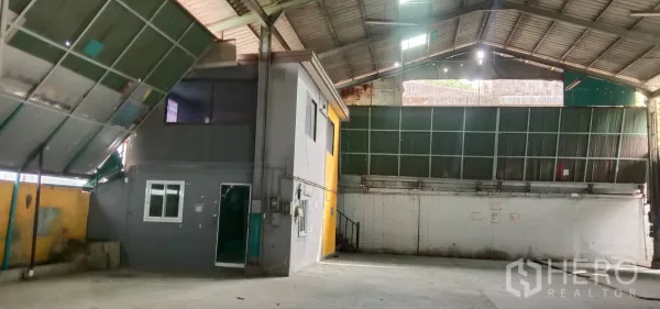 Warehouse for rent in Bueng Kum, Bangkok - Wide interior bay with ventilated metal wall panels, roller shutter entry and clear open floor ideal for storage or loading.