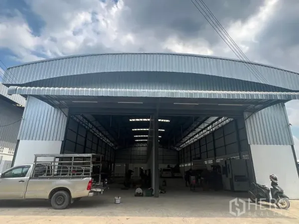 Warehouse for rent in Khlong Sam Wa, Bangkok - Front view of a modern steel-clad warehouse with twin wide openings, covered loading canopy and parking area in Khlong Sam Wa, Bangkok.