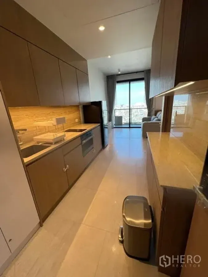 Condominium for rent - Kitchen corridor with full‑height storage, integrated appliances, and city‑view balcony ahead.