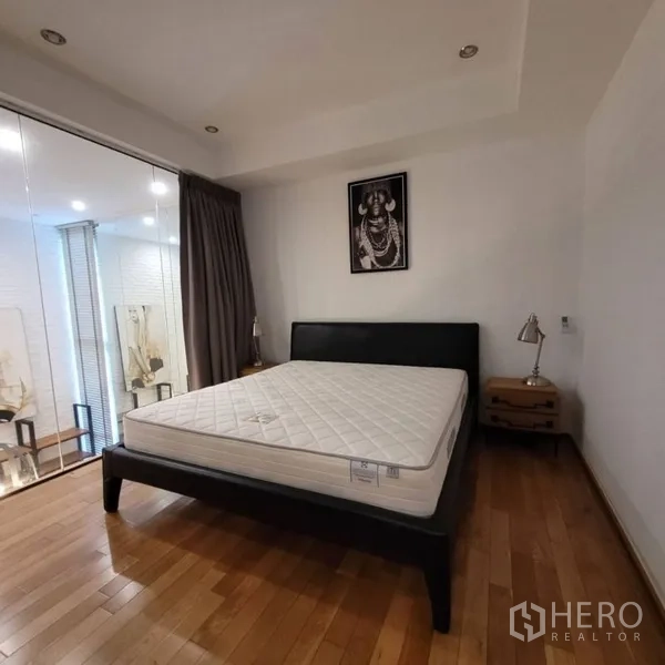 Condominium for rent in Khlong Toei, Bangkok - Bright bedroom with queen bed, glass wall, and floor-to-ceiling drapes.