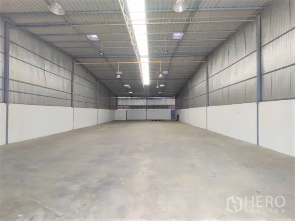 Warehouse for rent in Pathum Thani - Spacious clear-span warehouse interior with high steel roof, bright strip lighting and durable concrete floor.