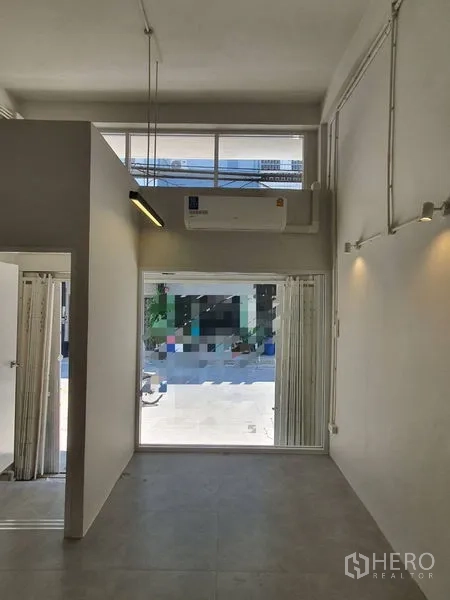 Shophouse for rent in Phra Khanong, Bangkok - Front retail area with floor-to-ceiling window, split air conditioner and tall ceiling.