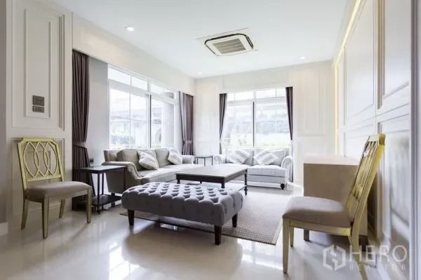 Detached House for rent in Mueang Samut Prakan, Samut Prakan - Bright living room with large windows, neutral decor, sofa set and a ceiling cassette air conditioner.