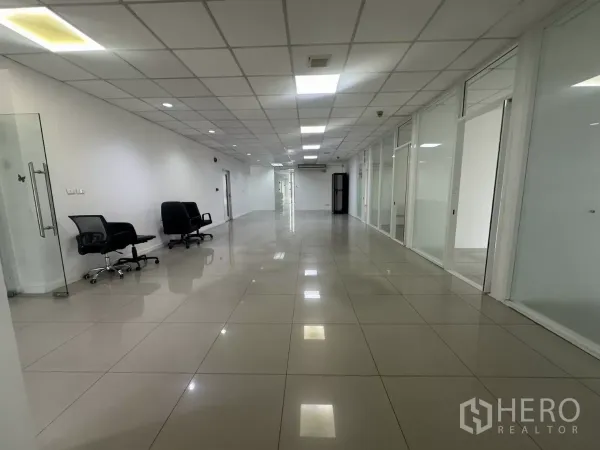 办公空间 出租在Huai Khwang, Bangkok - 长形开放办公区，摆放转椅，沿墙为玻璃办公室与光亮瓷砖地面。