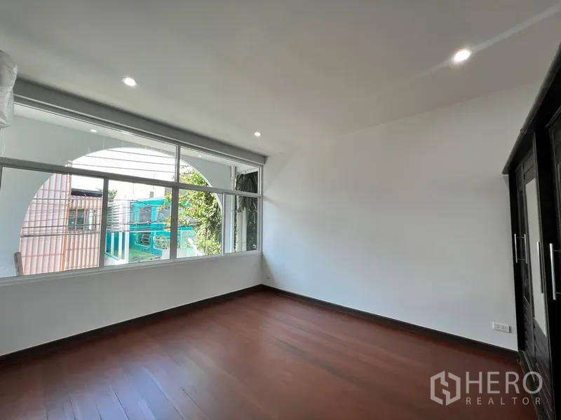 Home Office for rent in Watthana, Bangkok - Corner bedroom with wide windows bringing in natural light and neighborhood views.