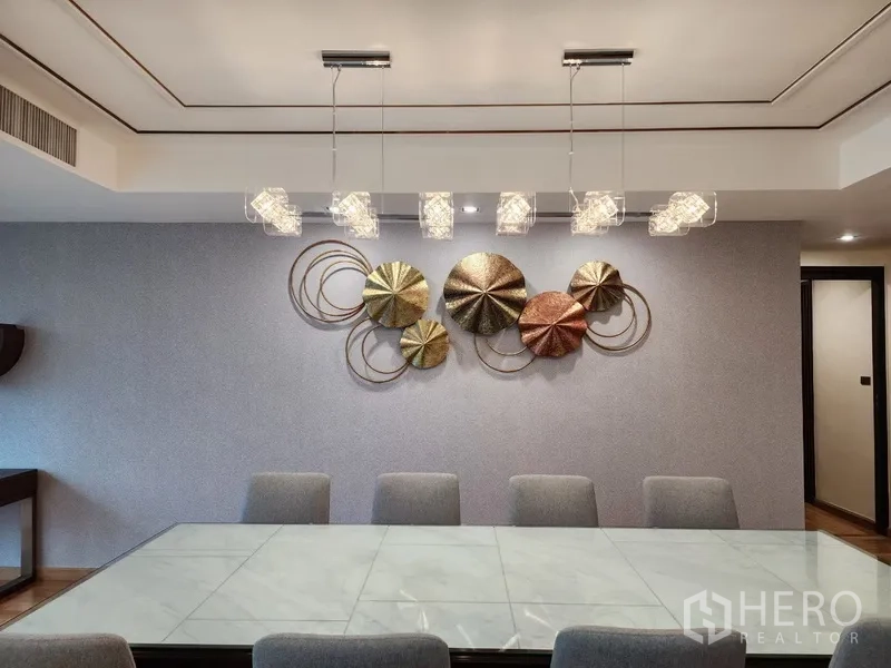 Condominium for rent in Khlong Toei, Bangkok - Art-accent wall and modern pendant lighting above dining table.