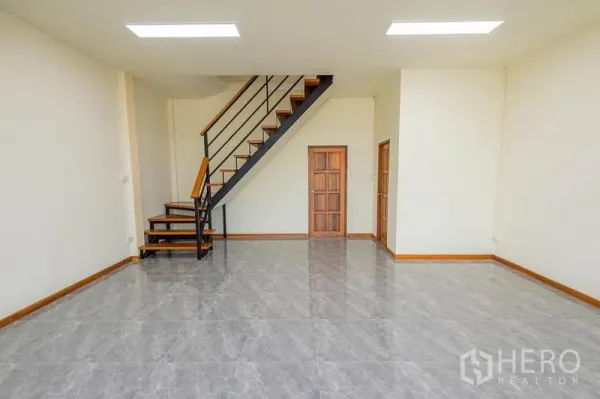 Factory for sale in Bang Sao Thong, Samut Prakan - Ground-floor office with glossy tile floors, staircase to the upper level and wooden internal doors.