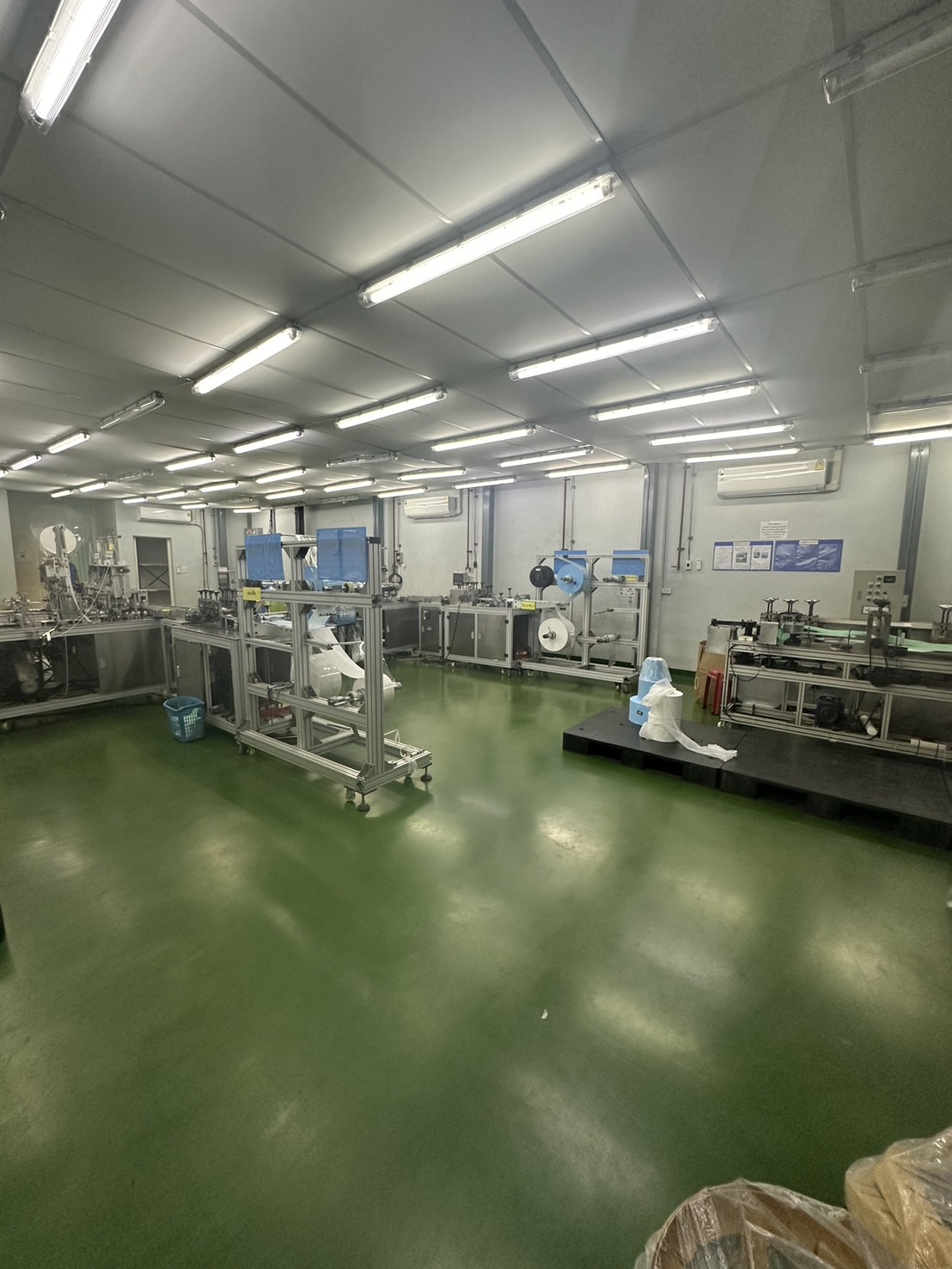 Warehouse for rent or sale in Lam Luk Ka, Pathum Thani - Manufacturing room with multiple machinery stations, air-conditioning and smooth green floor.