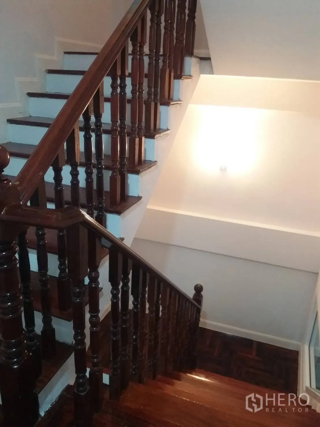 Townhouse for rent in Khlong Toei, Bangkok - Polished wooden staircase with classic balustrade and soft wall lighting.