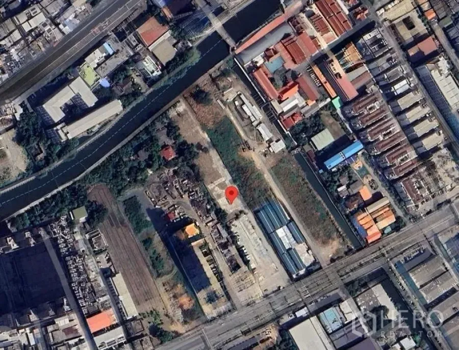 Land for rent in Bang Kapi, Bangkok - Aerial view of a vacant land plot in Hua Mak, Bang Kapi, Bangkok, beside a canal with nearby warehouses, roads, and mixed-use buildings.
