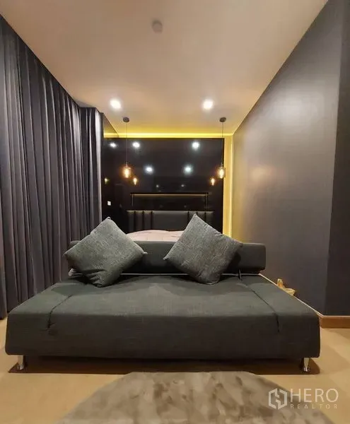 Townhouse for rent in Thanyaburi, Pathum Thani - Cozy bedroom with dark accent wall, pendant lights, and a gray sofa at the foot of the bed.