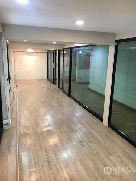Retail Space for rent in Watthana, Bangkok - Long showroom corridor with floor-to-ceiling glass walls and light wood floors.