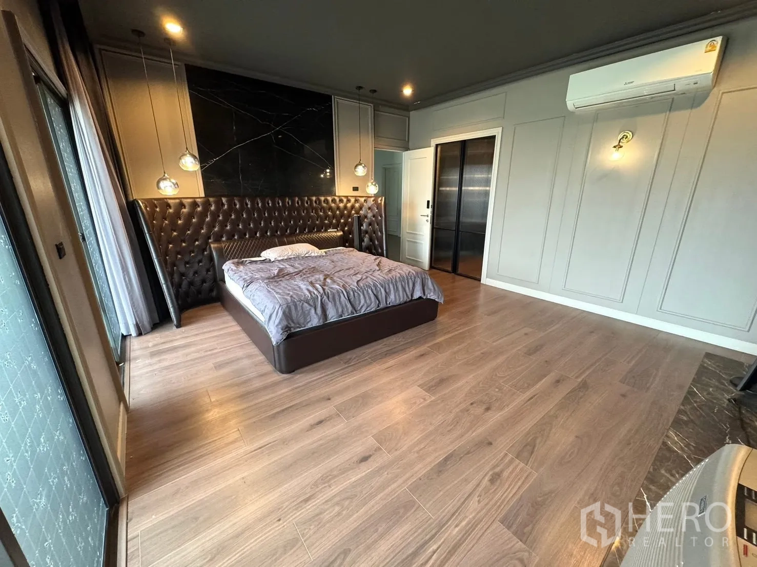 Detached House for sale in Mueang Pathum Thani, Pathum Thani - Master bedroom with tufted headboard, balcony door and air‑conditioner.