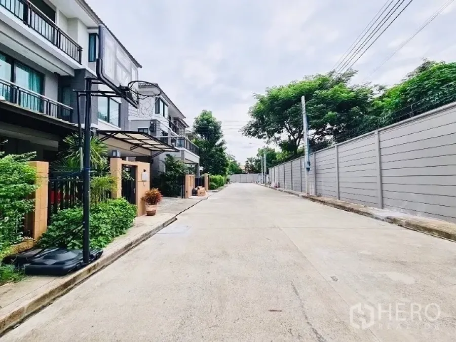 Detached House for sale in Suan Luang, Bangkok - Quiet residential lane in a gated community with modern three‑storey homes and greenery.