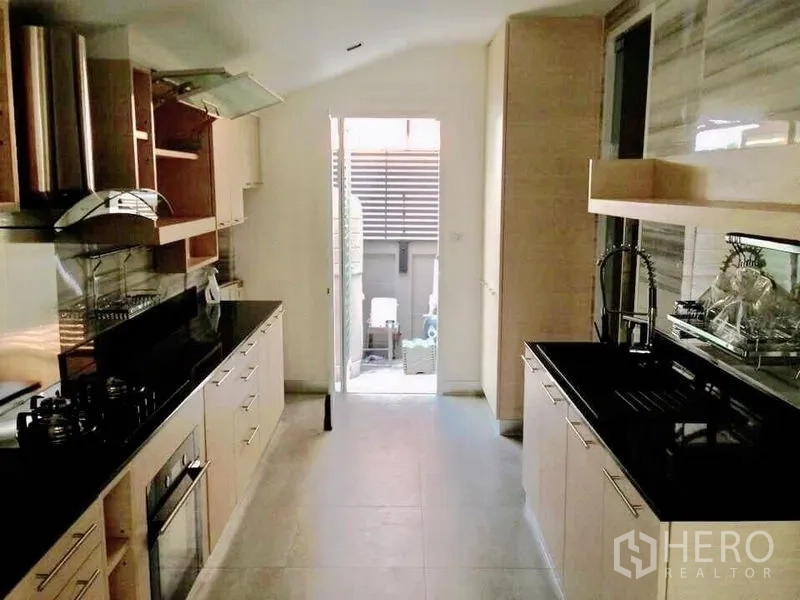 Detached House for rent or sale in Prawet, Bangkok - Separate galley Thai kitchen with gas hob, oven and door to a utility area.