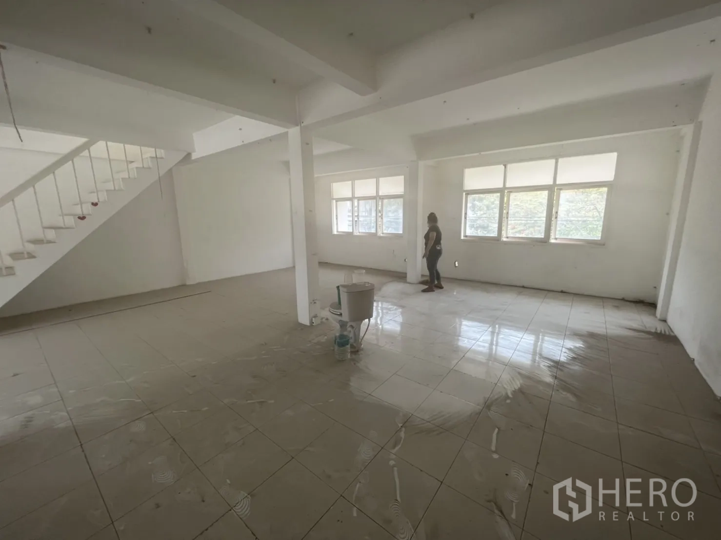 Shophouse for rent in Watthana, Bangkok - Bright tiled room with wide windows and a staircase, ideal for office use.