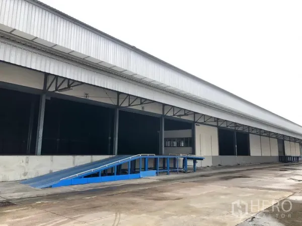 Warehouse for rent in Bang Phli, Samut Prakan - Dock-high loading bay with blue ramp and roller shutter doors at the industrial facility.