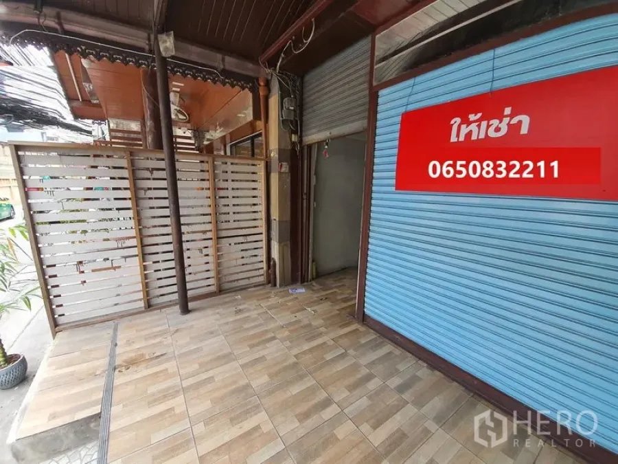 Shophouse for rent in Bang Rak, Bangkok - Street-facing storefront with covered patio, wood-look tiles and blue roller shutter with rental sign.
