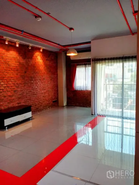 Office Space for rent in Khlong Toei, Bangkok - Loft-style office interior with exposed red pipes, brick feature wall and floor-to-ceiling windows.