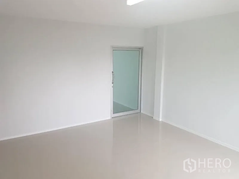 Shophouse for rent or sale in Lat Phrao, Bangkok - Minimal white room featuring a sliding glass door and smooth tiled floor.