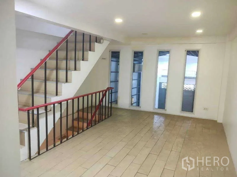 Shophouse for sale in Phra Khanong, Bangkok - Upper landing with stairs and four slim vertical windows.