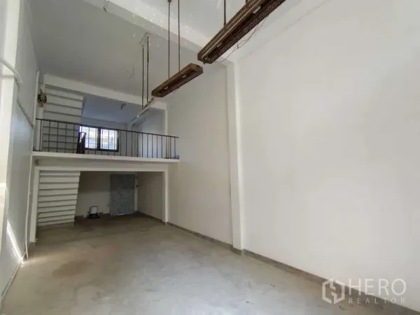 Shophouse for rent in Bang Na, Bangkok - Open-plan ground floor with hanging lights and mezzanine railing.