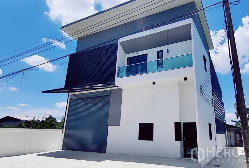 Warehouse for rent in Lam Luk Ka, Pathum Thani - Front facade of new warehouse with gray cladding, glass balcony and motorized roller door.