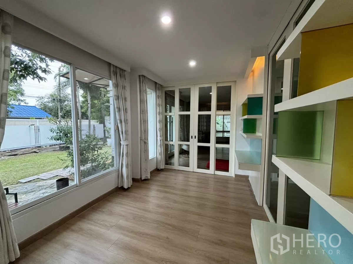 Detached House for rent in Bang Kapi, Bangkok - Sunroom with floor-to-ceiling windows and colorful display shelves.