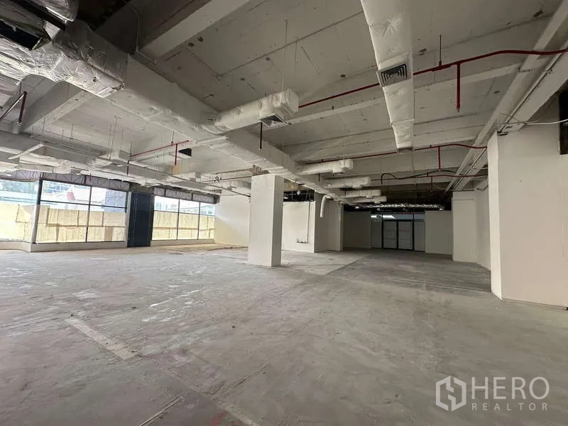 Office Space for rent - Large vacant office floor showing structural columns, insulated HVAC piping and broad glazing.