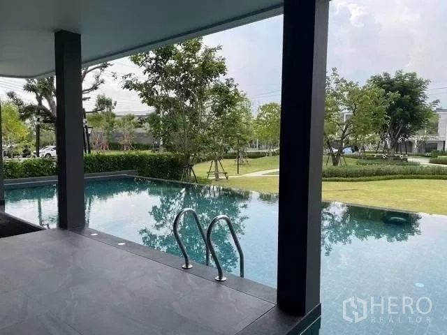 Townhouse for rent in Bang Phli, Samut Prakan - Covered-edge swimming pool overlooking green gardens and trees.