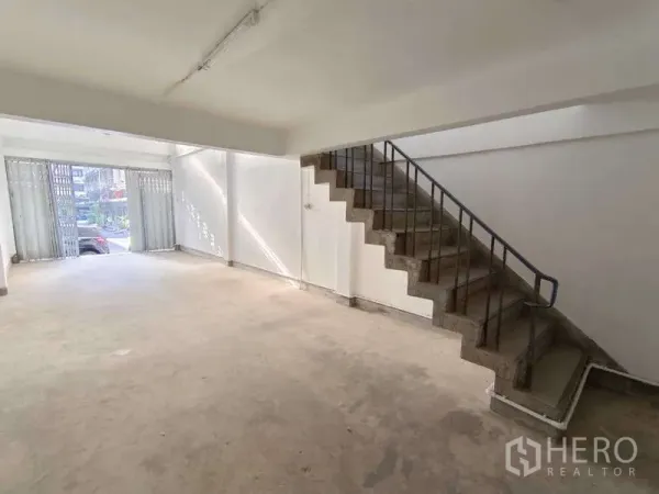 Shophouse for rent in Bang Na, Bangkok - Street-facing storefront with wide space and side staircase to upper floors.