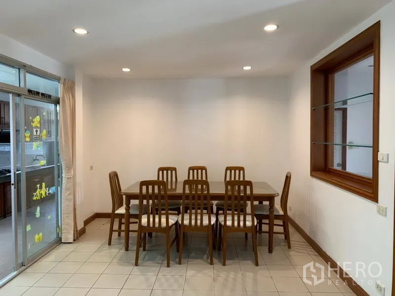 Detached House for rent in Khlong Toei, Bangkok - Dining area with six-seat table, recessed lighting and sliding glass door to the kitchen.