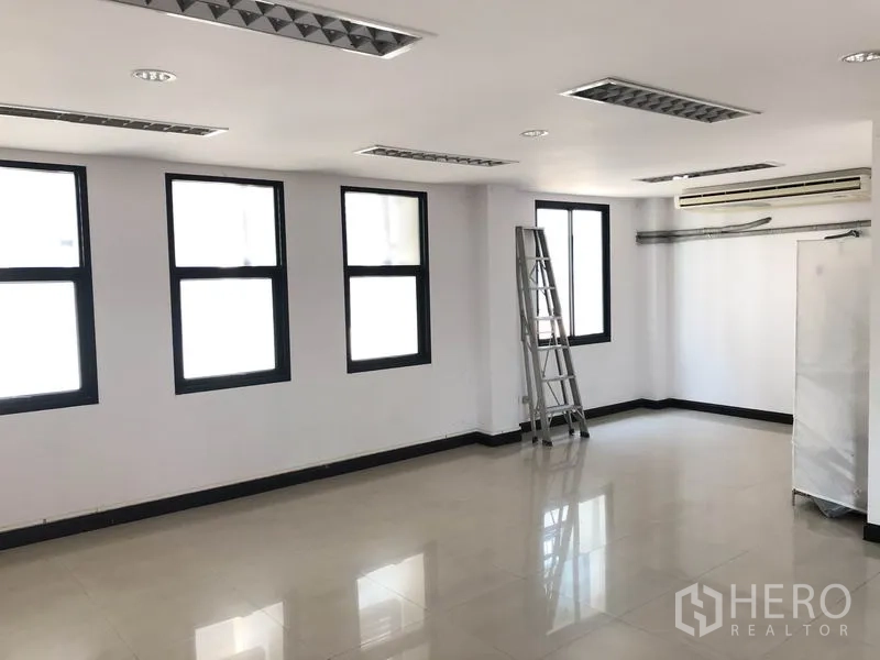Home Office for rent in Wang Thonglang, Bangkok - Empty office room with multiple black-framed windows, glossy flooring and ceiling lights.